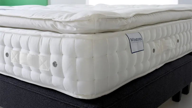 Ein Bild der Ultra Cotton 3500 Pillow Top Matratze von Winston in der Ecke.