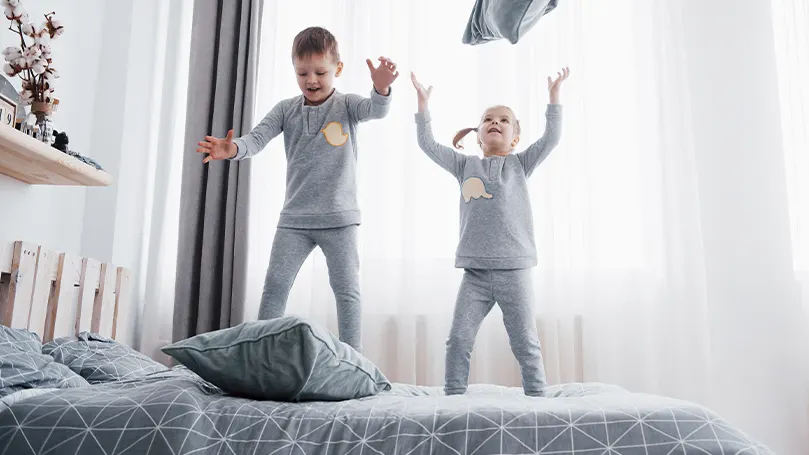 Ein Bild von zwei kleinen Kindern, die auf dem Bett herumspringen.